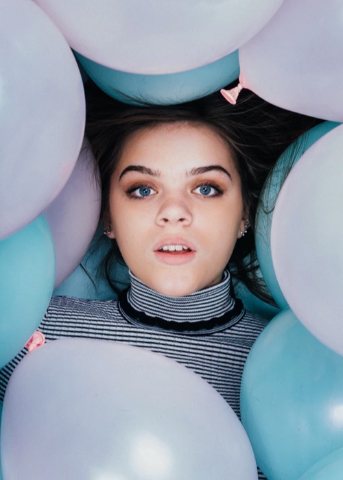 Woman laying in balloons staring upwards